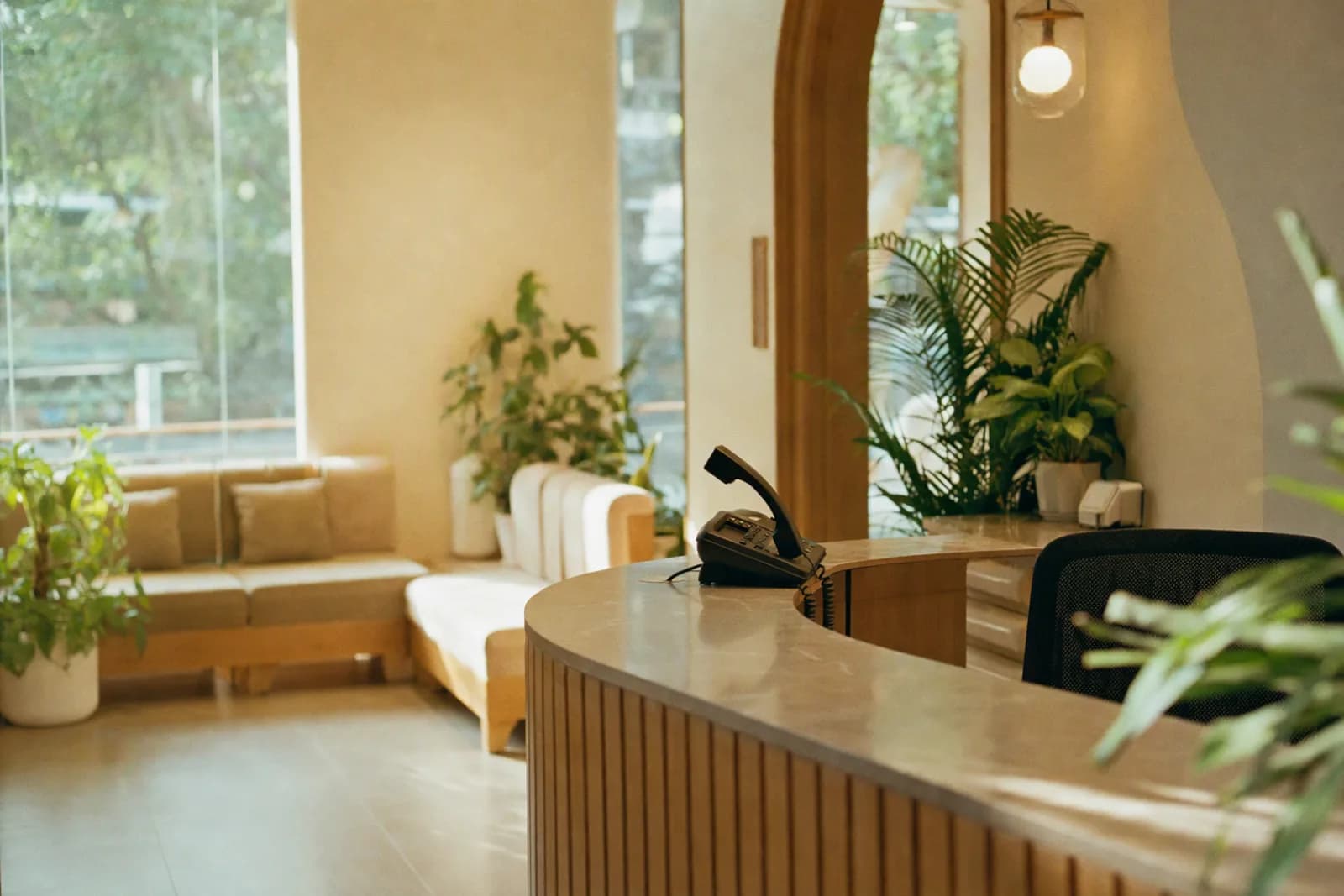A quiet dental clinic reception in morning light, the phone handset slightly lifted as if a call is coming in